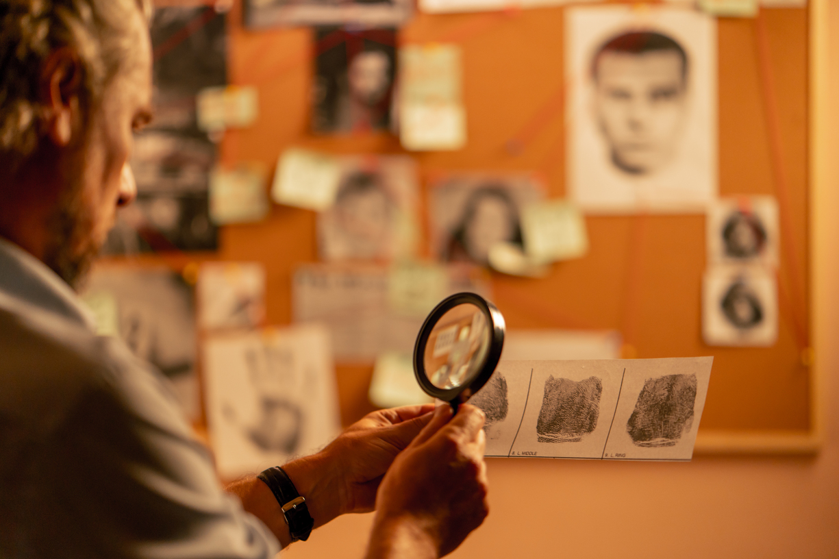 Detective privado revisando documentos y fotografías sobre una mesa en una oficina moderna en Murcia, concepto de servicios profesionales